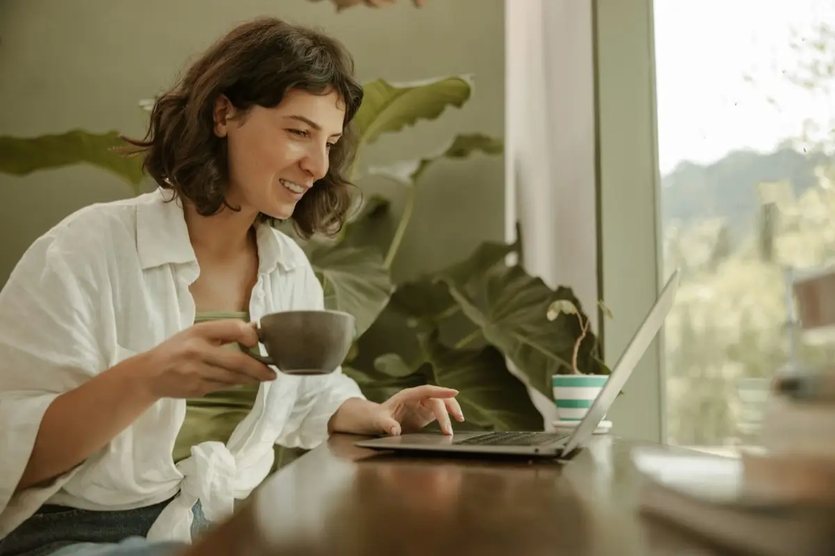 A person replying to a review at a laptop with a coffee cup nearby